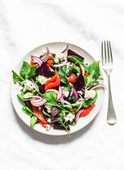 Beetroot, smoked salmon, arugula, soft cheese salad on a light background, top view