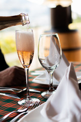 champagne bottle served in full glasses next to empty glass in celebration of marriage near window with landscape on restaurant