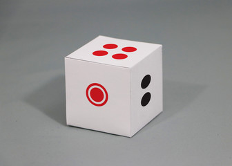 Paper dice on grey background. four points up with one and two.