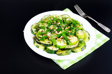 Fried zucchini with green greens, garlic and walnuts.