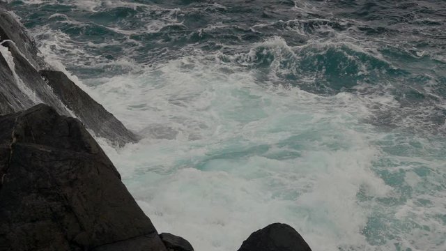 Big wave splashing against land in western Norway. Slow motion and close up.