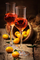Traditional greek kumquat liqueur in shot glass, vintagen background, rustic style, selective focus