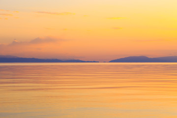Fototapeta premium Beautiful sunset on a lake in the mountains. Kyrgyzstan, Issyk-Kul Lake. Bright sky, background in warm colors.