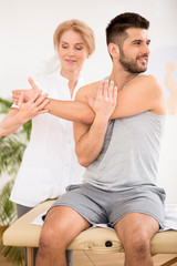 Handsome young man during physiotherapy session with professional doctor