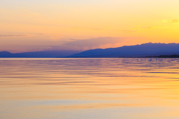 Fototapeta na wymiar Beautiful sunset on a lake in the mountains. Kyrgyzstan, Issyk-Kul Lake. Bright sky, background in warm colors.