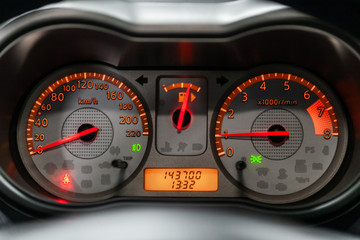 close-up of round dashboard, speedometer and tachometer with orange backlight. modern car interior.
