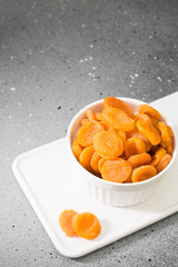 Dried apricots in a white bowl on a gray table