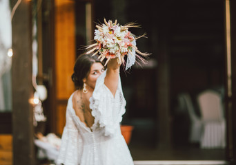 Beautiful smiling bride brunette young woman in white lace dress throwing wedding bouquet