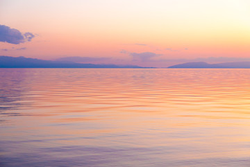 Beautiful sunset on a lake in the mountains. Kyrgyzstan, Issyk-Kul Lake. Bright sky, background in warm colors.