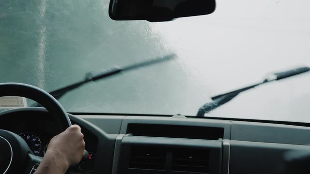 The driver drives the car into heavy rain, jets of water flow along the windshield, the windshield wipers do not have time to wash it off