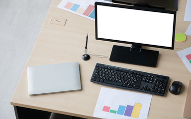Computer pc with blank screen destop, laptop, paperwork and office supplies on wooden table desk with no employees. Modern creative workspace background.