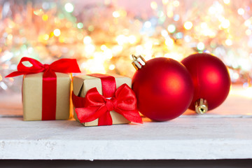 New Year. Red balls to decorate the Christmas tree and a gift with a red bow. Bokeh on the background.