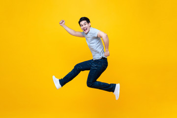 Fototapeta na wymiar Fun energetic young handsome Asian man jumping in mid-air