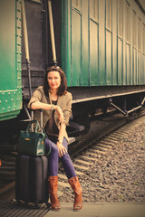 Fototapeta na wymiar woman with a suitcase and handbag sitting on the steps of the passenger railroad retro wagon
