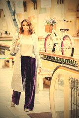 woman in a light knitted coat and purple trousers