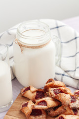Milk glass and biscuit cookies with kitchen cloth on light background