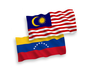 National vector fabric wave flags of Venezuela and Malaysia isolated on white background. 1 to 2 proportion.