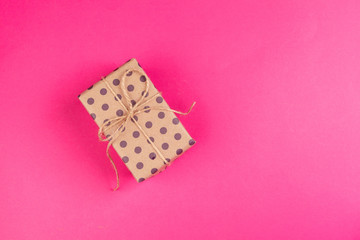 Top view of a decorated present with a bow on pink background