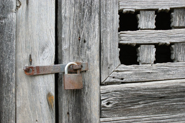 antique wooden window closed by an old rusty lock