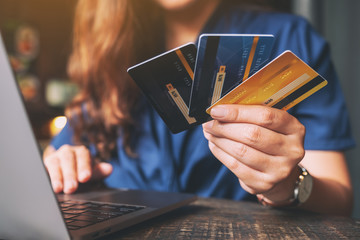 A woman holding credit cards while using laptop computer