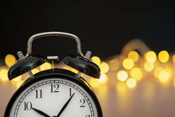 Close up of retro alarm clock on blurred Christmas background with bokeh