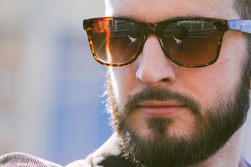 Bearded trendy young businessman in a suit and sunglasses with a reflection of a basketball ball with glasses. Sports and active lifestyle office worker. Bearded hipster holding a basketball.