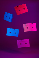 Colored audio cassettes hanging in the air against purple background