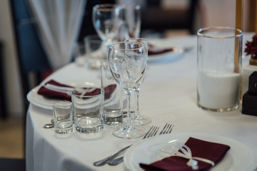 Glasses, flower fork, knife served for dinner in restaurant with cozy interior