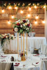 A composition of flowers and green is on a festive table at the wedding banquet hall.