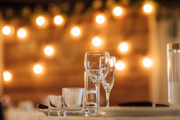 Glasses, flower fork, knife served for dinner in restaurant with cozy interior