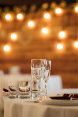 Glasses, flower fork, knife served for dinner in restaurant with cozy interior