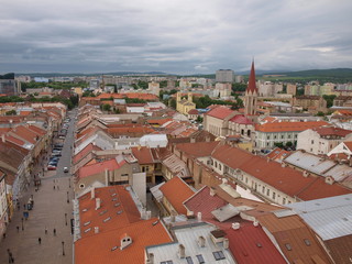 Fototapeta premium view of the old part of the city from above, on the roofs of houses made of brown tiles, the spire of the Church and the street.