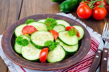Diet salad of fresh cucumbers and tomatoes, cut into slices on wooden table