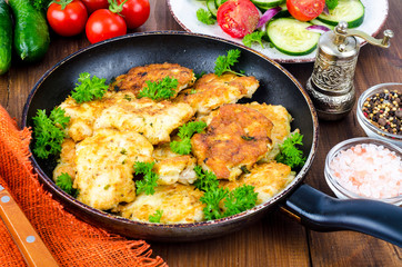 Fried meat pancakes in pan, vegetables, wooden background