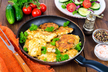 Fried meat pancakes in pan, vegetables, wooden background