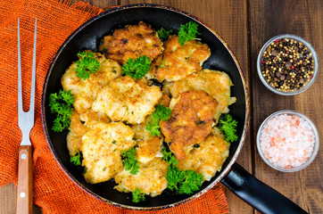 Fried meat pancakes in pan, vegetables, wooden background