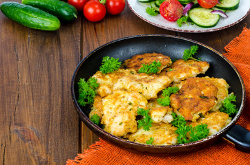 Fried meat pancakes in pan, vegetables, wooden background