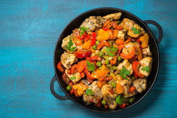 Chicken Stir fry with vegetables on blue table.