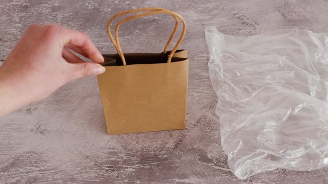 hand placing paper shopping bag next to plastic bag into the scene