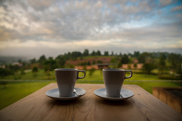 happy hipster lover couple guiding resting relaxing drinking coffee together  at beautiful blue sky mountains hills green forest scenery garden park  grass field outdoor views Kanchanaburi, Thailand.