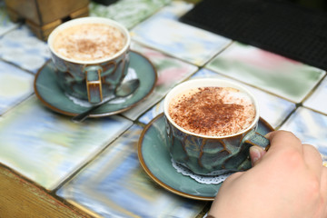 Woman with cups of fresh coffee at table, closeup