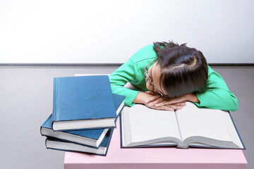 Asian cute girl with glasses fall asleep on a book on the desk