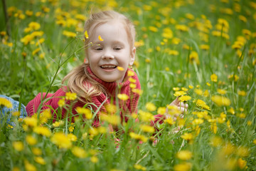 Little girl and meadow with dandelions. Summer day outdoors