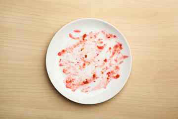 Dirty plate with food leftovers on wooden background, top view