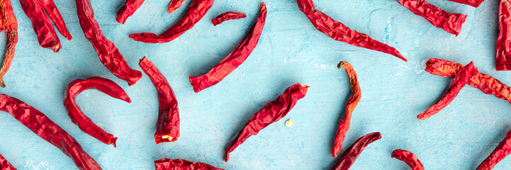 Dry red hot peppers on a blue background, overhead panoramic shot