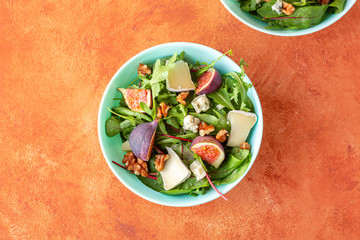 autumn harvest fig salad with cheese and walnuts on bright vibrant background. top view