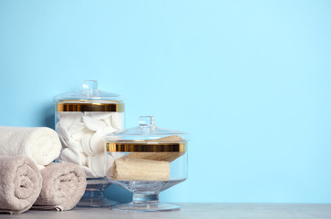 Composition of glass jar with cotton pads on table near blue wall. Space for text