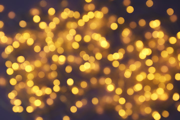 Blurred view of glowing Christmas lights on violet background