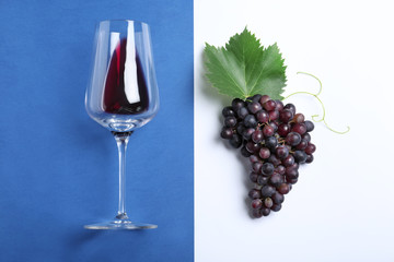 Fresh ripe juicy grapes and glass of wine on color background, flat lay