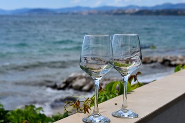Romantic glasses of cold white wine served on outdoor terrace whit beautiful sea view/ beach view/ Conceptual image of summer vacation